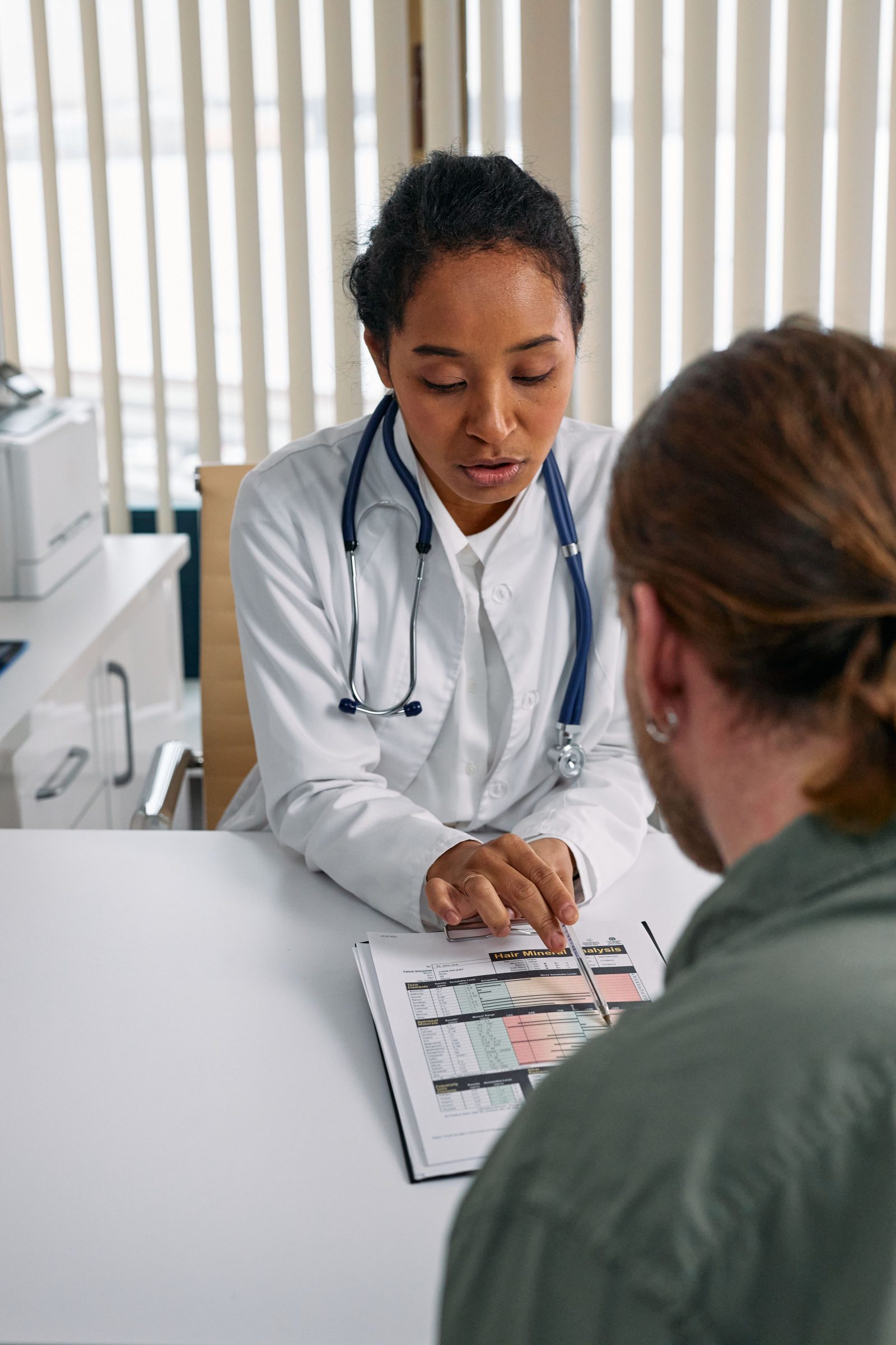 A doctor in a white coat speaking with a patient during a consultation
