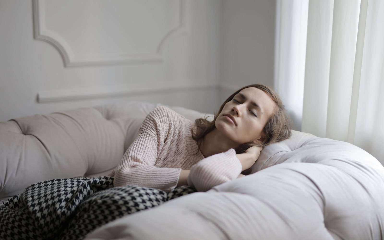 A woman resting on a sofa in daylight, low on energy