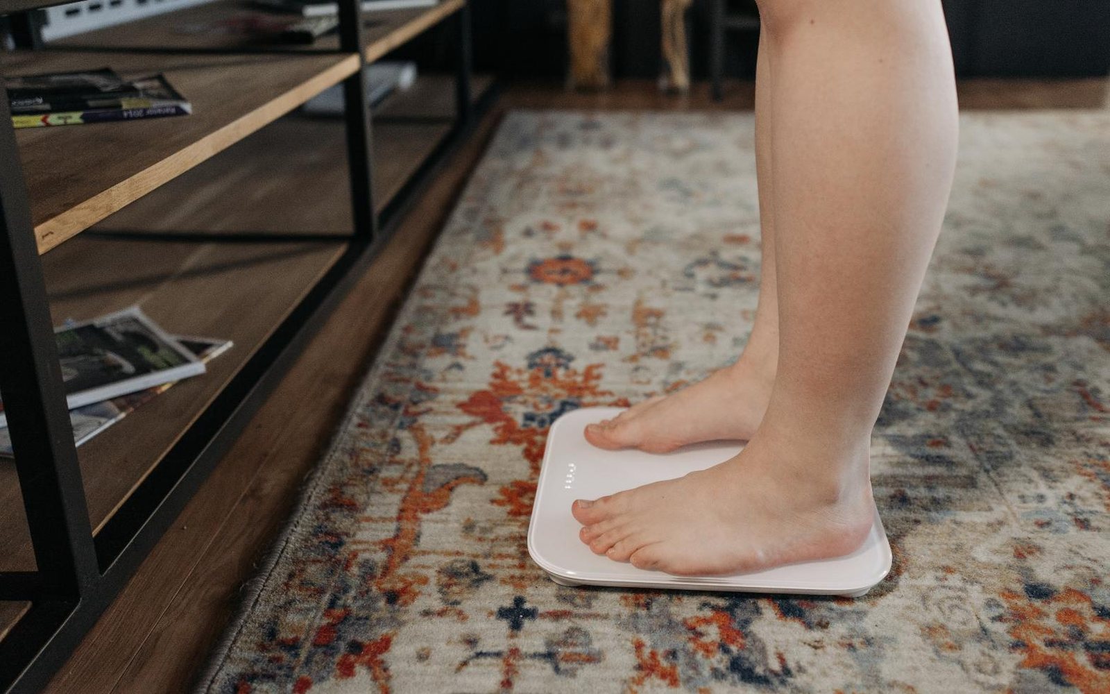 Bare feet stepping onto a bathroom scale on a patterned rug