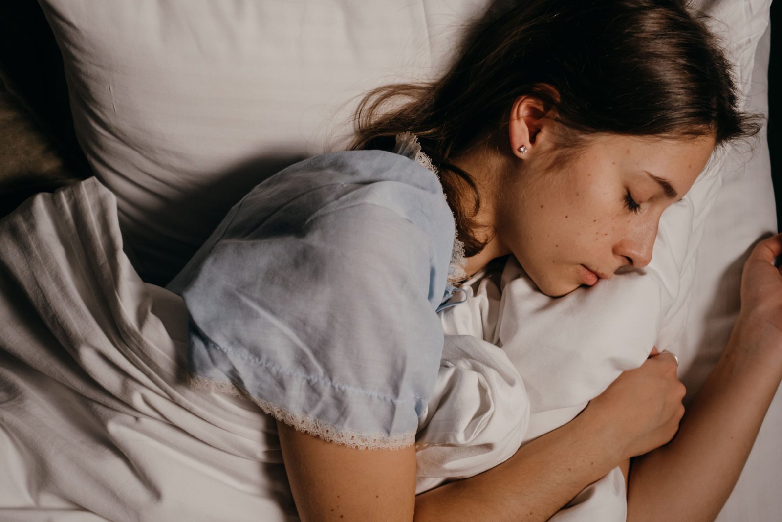 A woman sleeping peacefully in bed under soft light