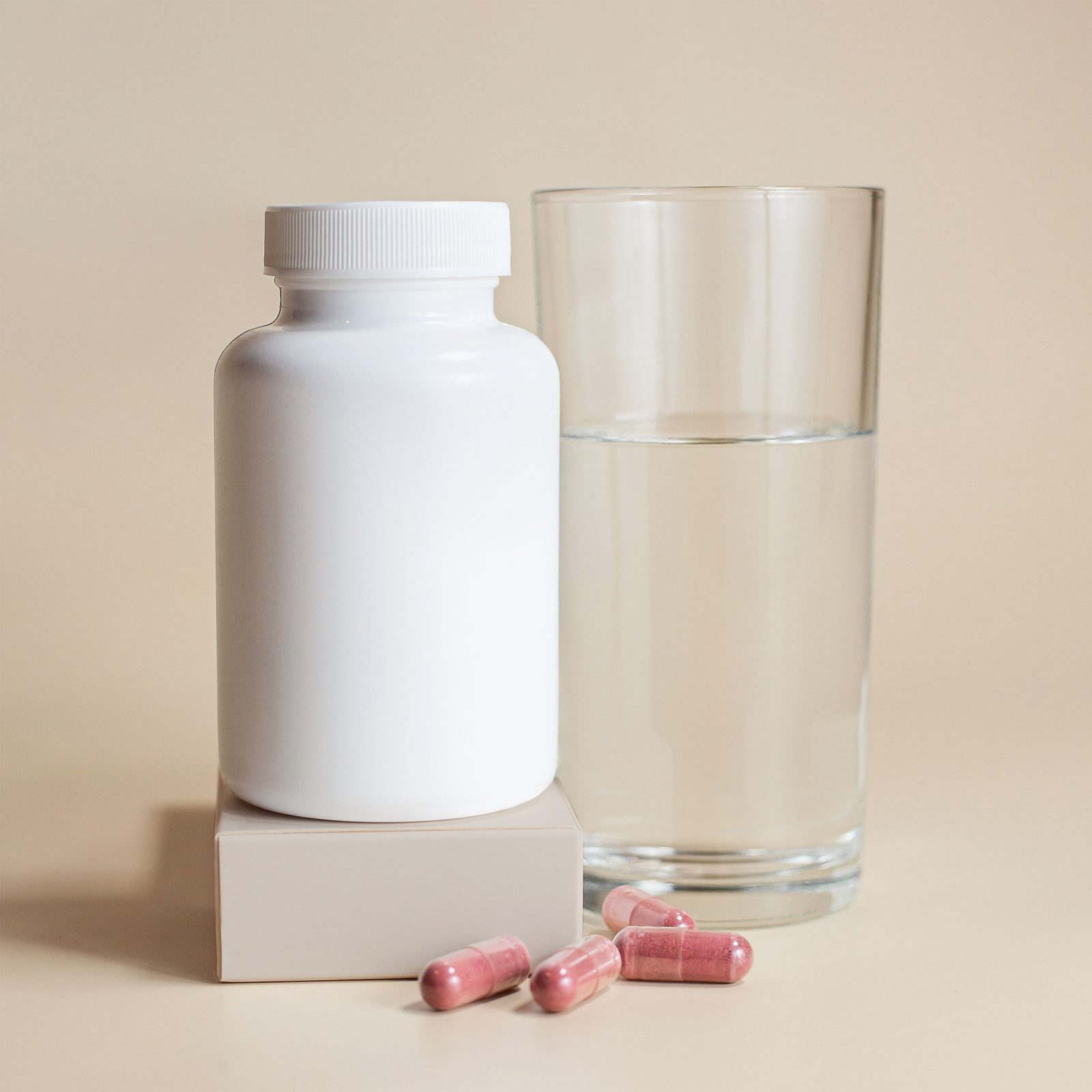 A white medication bottle beside a clear glass of water