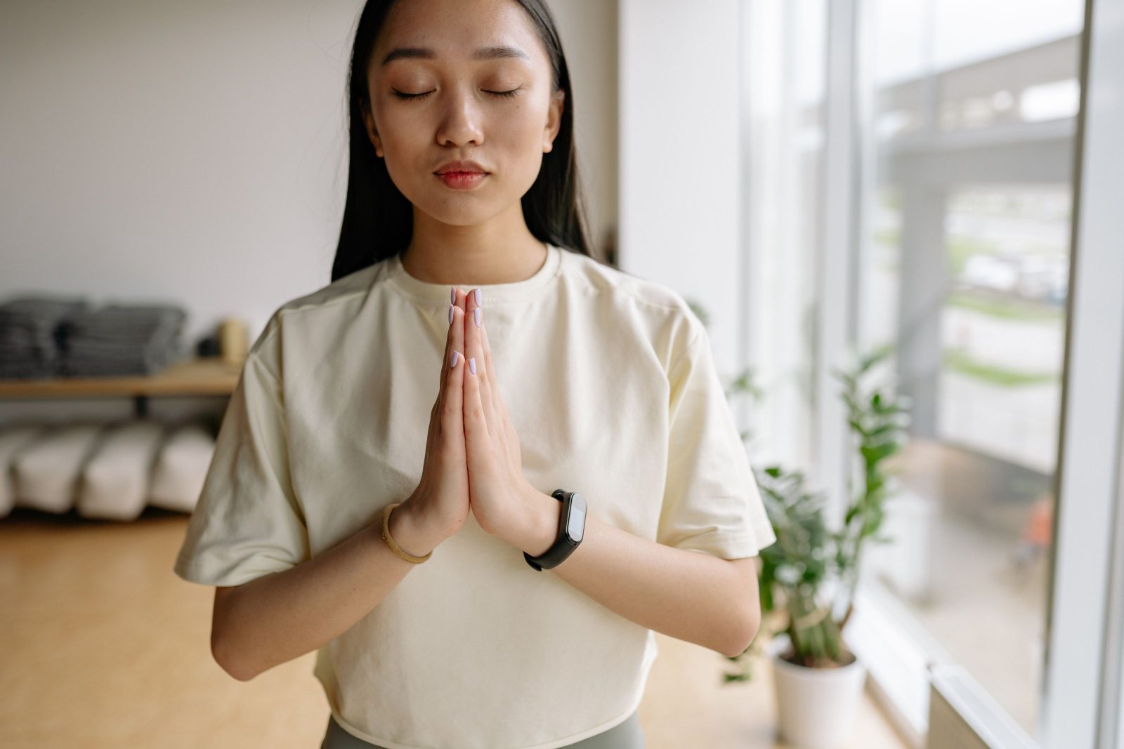 A woman with hands together in a calm breathing practice indoors