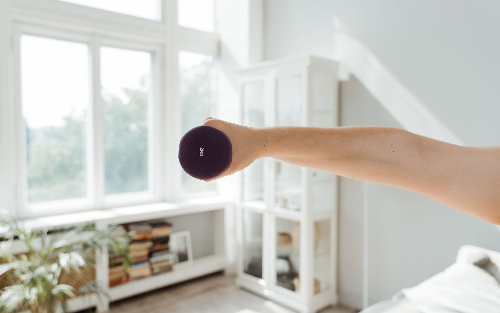 A woman training with a dumbbell in a bright room
